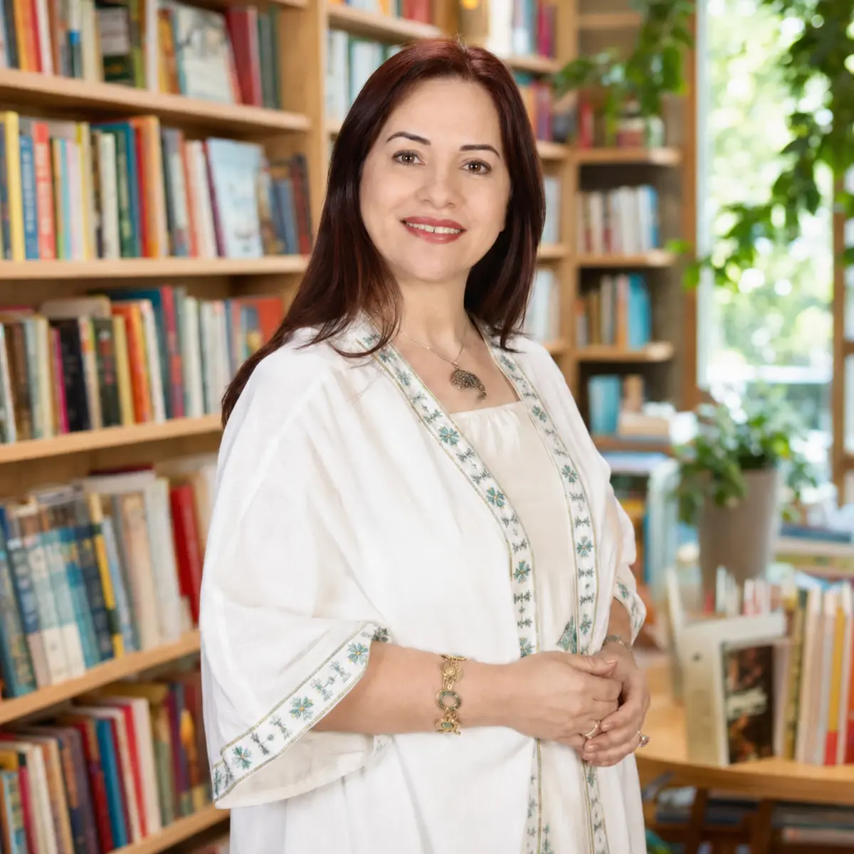 پرتره روبه‌روی نغمه فرج‌اللهی در کتابفروشی روشن و رنگی | Front-facing portrait of Naghmeh Farajollahi in a bright colourful bookshop